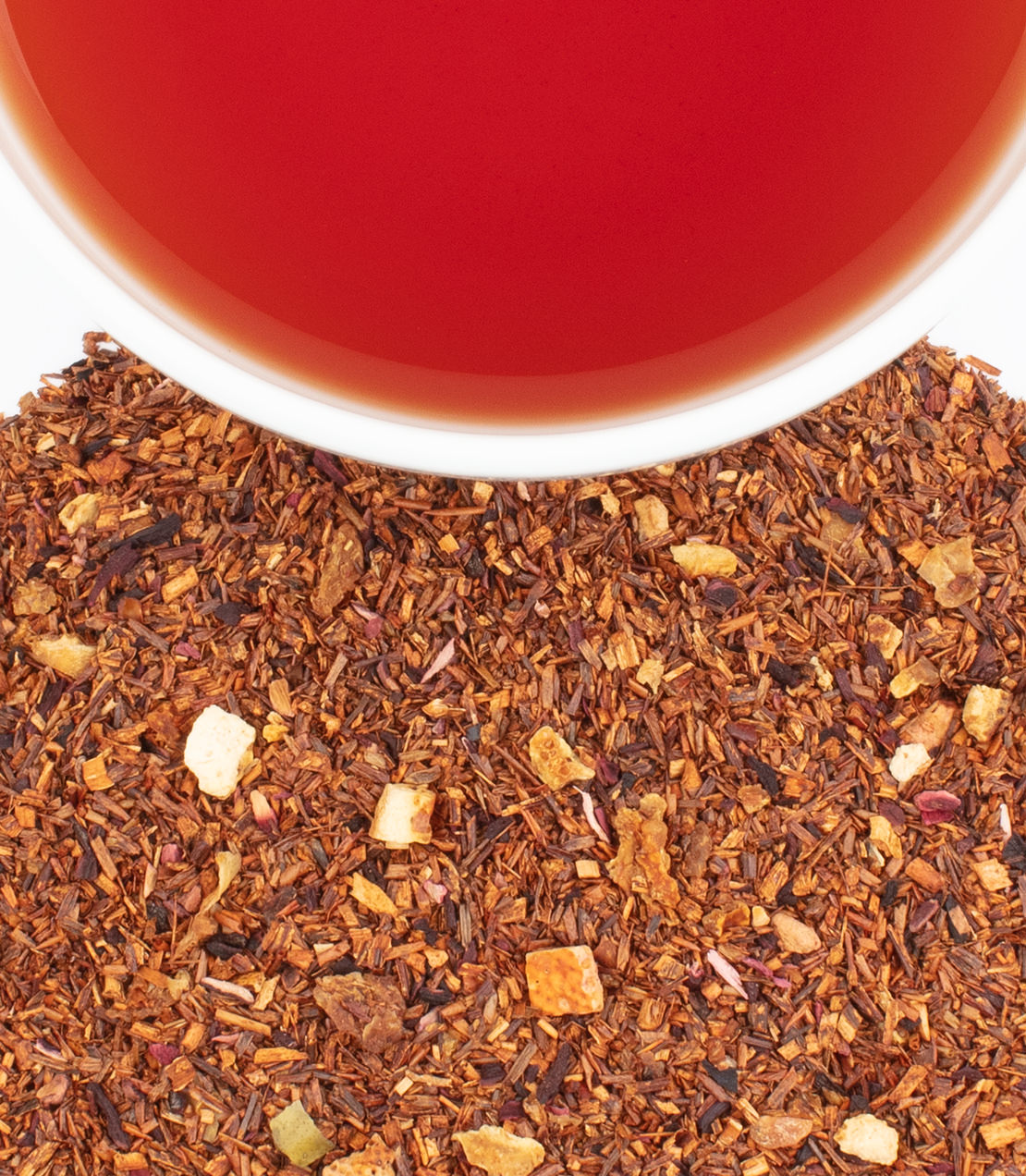 Alt text: Close-up view of the African Autumn tea from HRP, featuring a cup of brewed tea with a deep red hue surrounded by scattered dry tea leaves and herbal pieces, showcasing the rich color and texture of the blend.